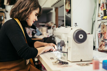 Young fashion designer using sewing machine