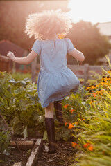 Back view of happy little girl jumping in the garden