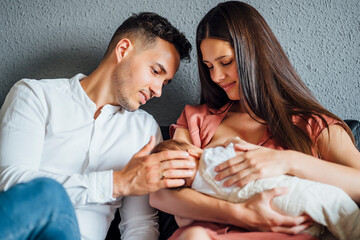Father looking at baby boy being breastfed by mother at home