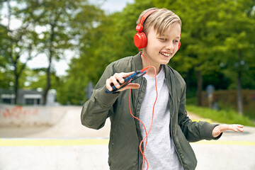 Boy with headphone dancing while listing to music on smartphone