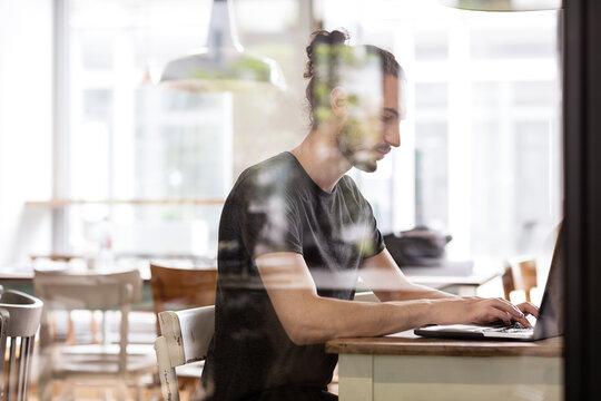 Man Using Laptop Behind Glass Wall