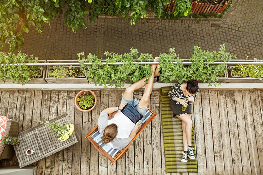 Young couple relaxing on their balcony in summer, man using tablet