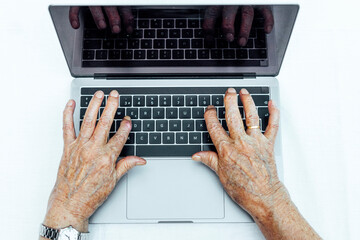 Close-up of senior woman's hands using laptop on table