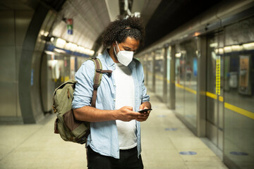Young man wearing protective mask standing at underground station platform, London, UK