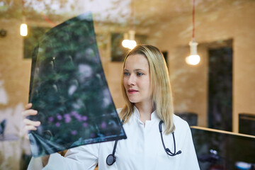 Female doctor looking at x-ray image behind windowpane