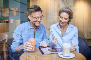 Happy woman and man using tablet in a cafe