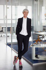 Portrait of fashionable senior businesswoman wearing pantsuit and sneakers in office