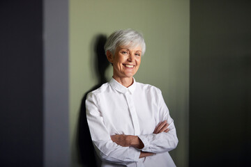 Portrait of carfree senior businesswoman leaning against wall