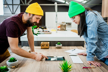 Business couple using digital tablet while bending over desk in modern office