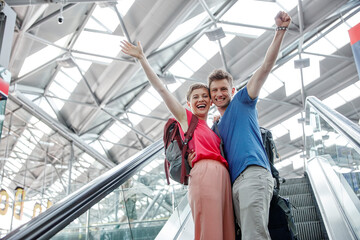 Happy couple cheering on escalator at the airport