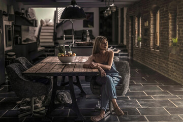 Woman sitting at dining table in her country house, thinking