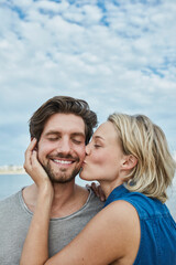 Happy young couple kissing on the beach