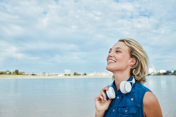 Germany, Duesseldorf, happy young woman with headphones at Rhine riverbank