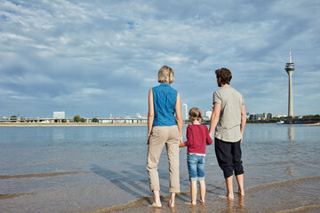 Germany, Duesseldorf, family with daughter standing at Rhine riverbank