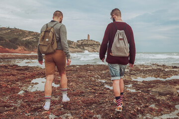 Spain, Oropesa del Mar, two young men walking on stony beach