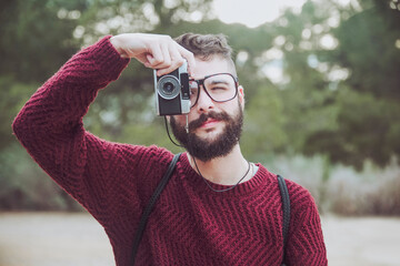 Portrait of bearded man with glasses taking photo with vintage camera