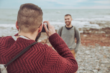 Man taking photos of his boyfriend in front of the sea