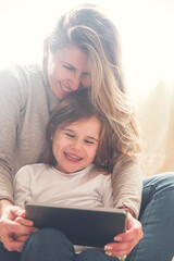 Mother and little daughter using tablet at home