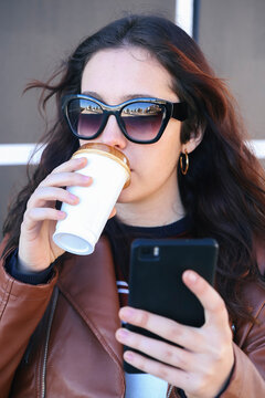 Portrait of young woman with coffee to go taking selfie with smartphone