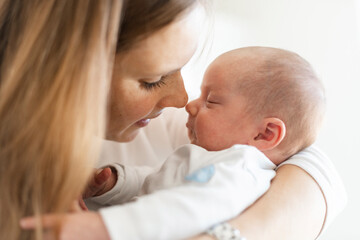 Close-up of mother embracing sleeping baby boy in arms at home