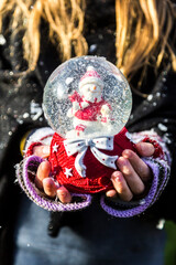 Girl's hands holding snow globe with snowman, close up