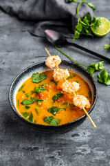 Bowl of sweet potato soup with shrimps, coconut flakes and fresh coriander