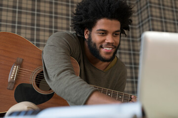 Man with guitar looking at laptop