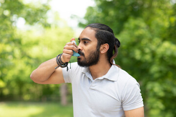 Young man in nature using asthma inhaler - obrazy, fototapety, plakaty