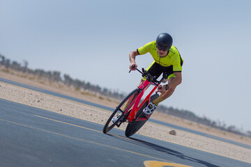 Determined cyclist riding bicycle on road against clear blue sky at desert in Dubai, United Arab...