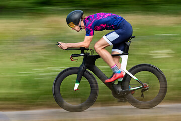 Triathlete riding bicycle on country road, Germany