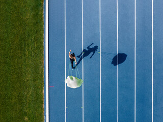 Top view of female runner with parachute on tartan track