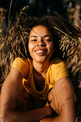 Close-up of smiling young woman with afro hair sitting in forest