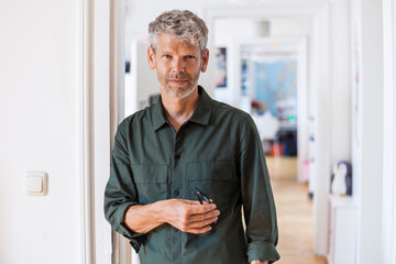 Portrait of mature man with grey hair and stubble at home