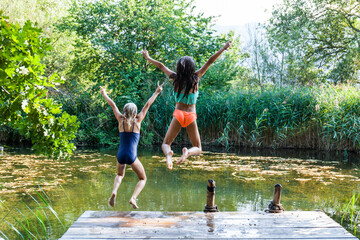 Fototapeta na wymiar Two carefree girls jumping into pond