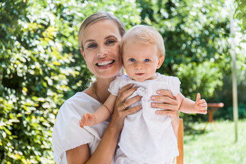 Portrait of happy mother holding her baby girl outdoors