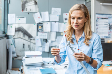 Confident woman in office holding wind turbine model