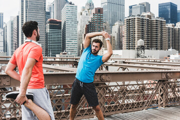 USA, New York City, two athletes stretching on Brooklyn Brige