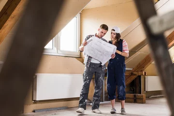 Foto op Plexiglas Young couple on construction site of their new home, looking at construction plan © tunedin
