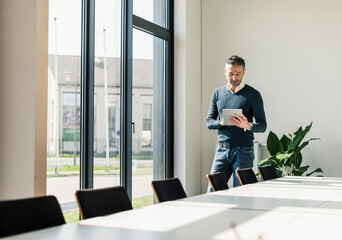 Businessman standing in conference room using tablet
