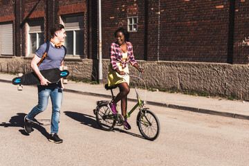 Young couple with bicycle and skateboard walking in the street