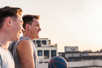 Friends playing basketball at sunset on a rooftop