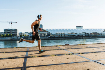 Young athlete jogging in the city at the river