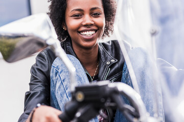 Portrait of smiling young woman with her motorcycle