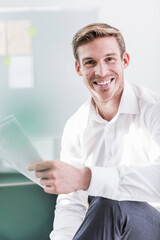 Portrait of smiling businessman in office holding documents