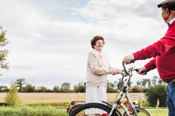 Senior man and woman with bicycles meeting in rural landscape