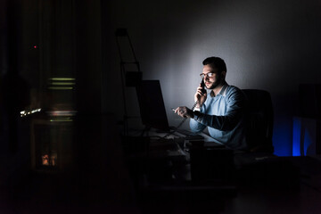 Businessman on the phone in office at night