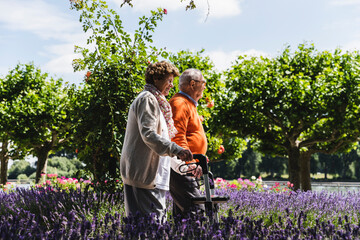 Senior couple walking in park, woman using wheeled walker