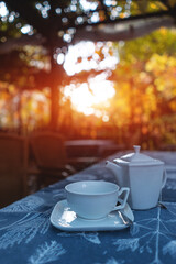 teapot with cup on table at park outdoor, fresh breakfast at sunset