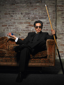 Portrait of Man on Sofa with Pool Cue and Billiard Balls