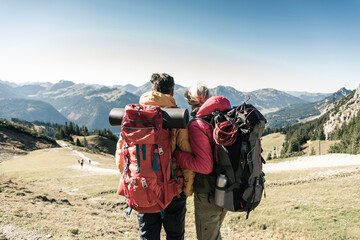 Austria, Tyrol, rear view of couple on a hiking trip in the mountains enjoying the view - obrazy, fototapety, plakaty